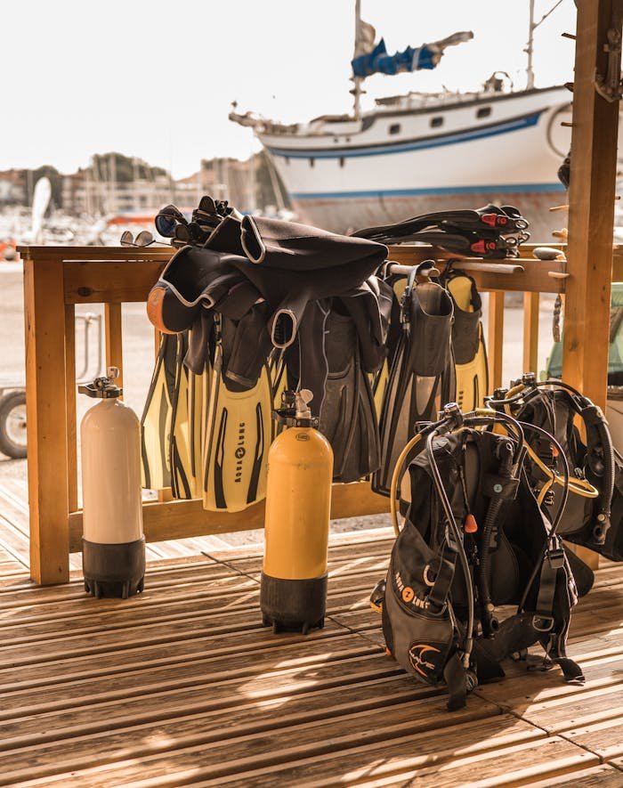 Dive equipment including tanks, fins, and snorkels set up near marina dock.