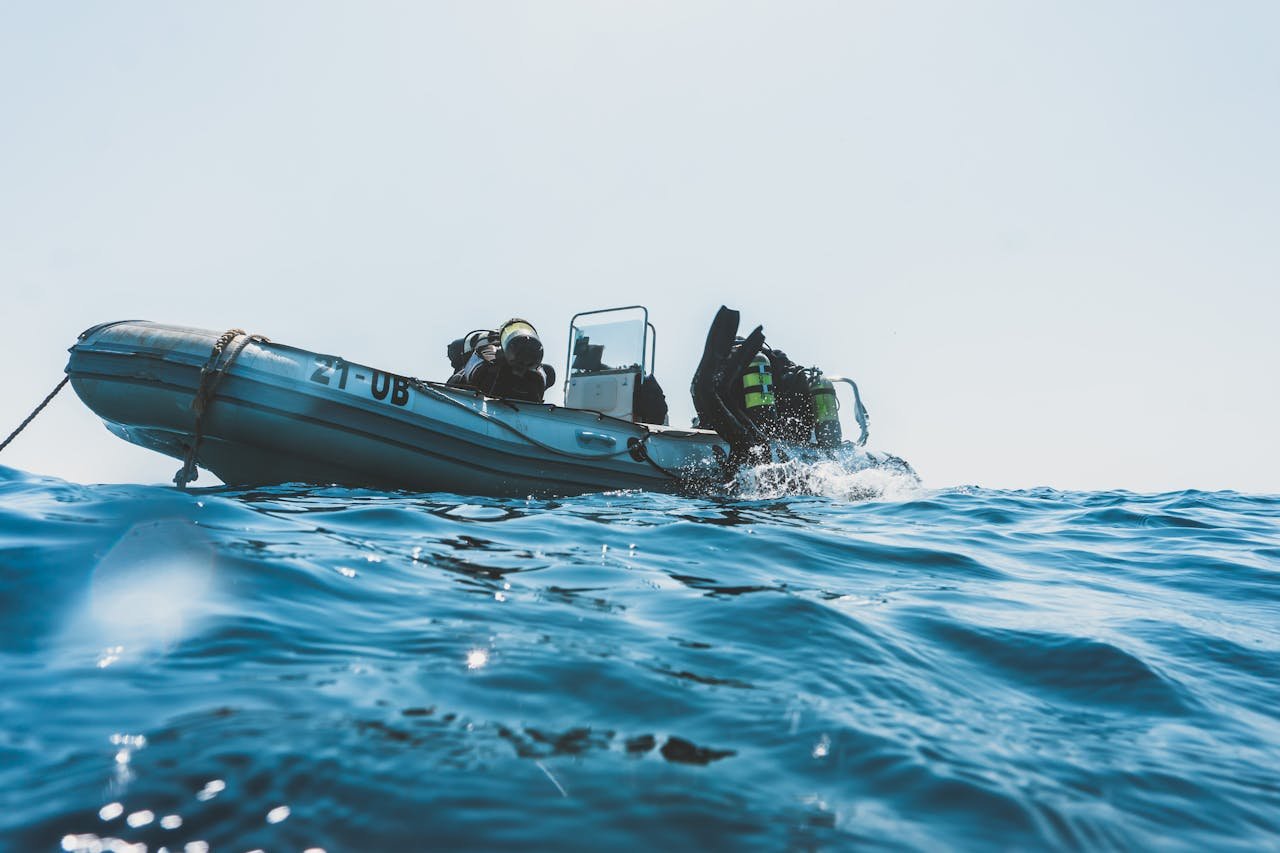 Scuba divers equipped for an ocean dive prepare from an inflatable boat on a sunny day.