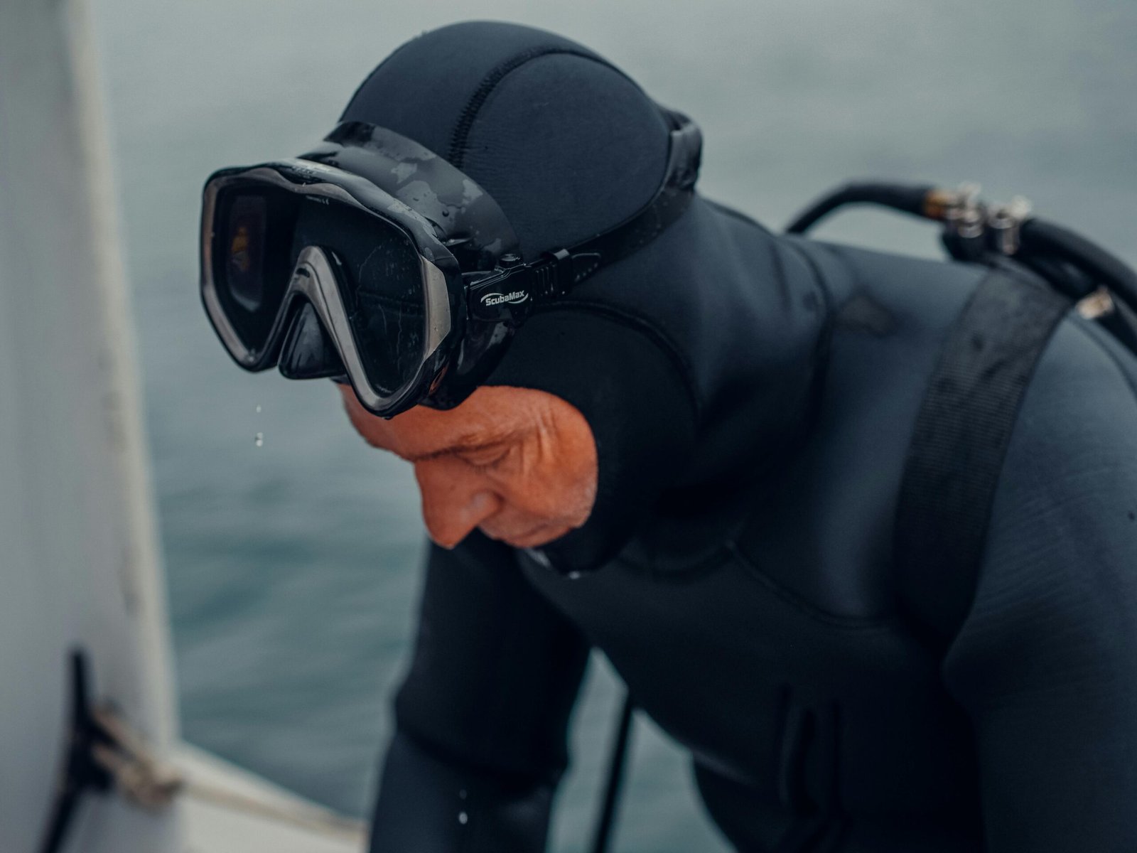 A scuba diver in a black wetsuit and mask prepares for an underwater expedition.